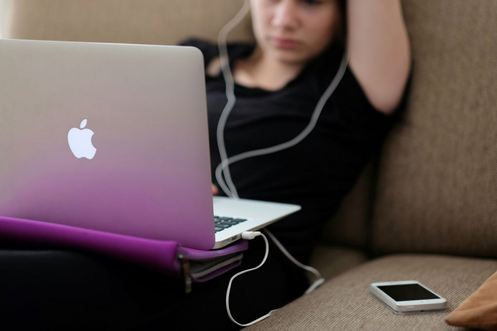 Woman on laptop with wired headphones on a couch